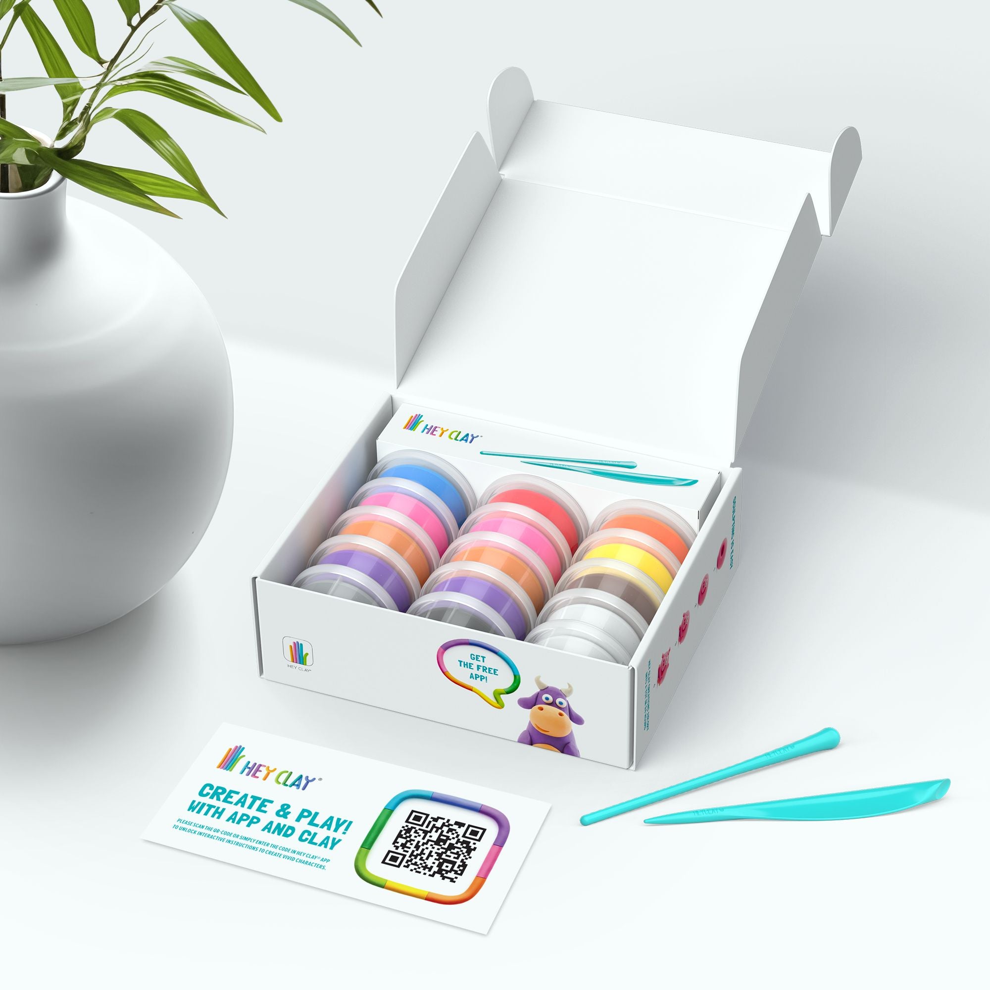 Box of colorful clay rolls with a plant and card in the background