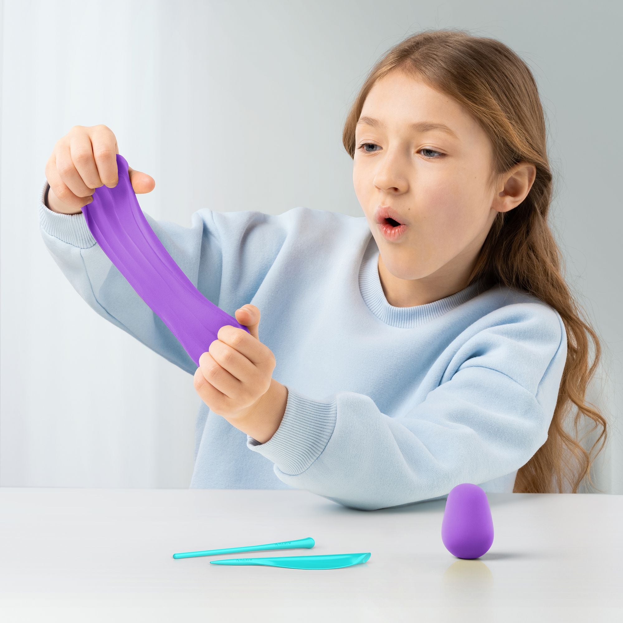 Child playing with a purple hey clay unicorn set