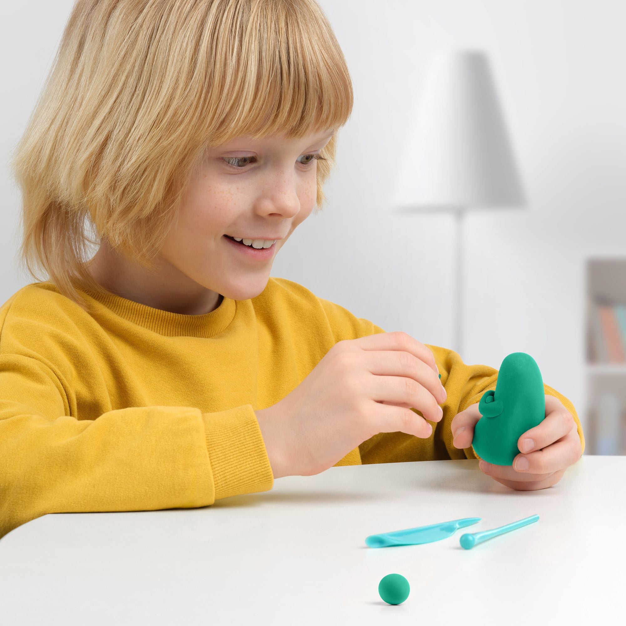 Child playing with green play hey clay creating hey clay monster