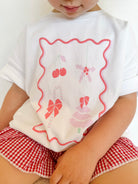 Rosie wearing Christmas  stamp tee and cherry red gingham shorts 