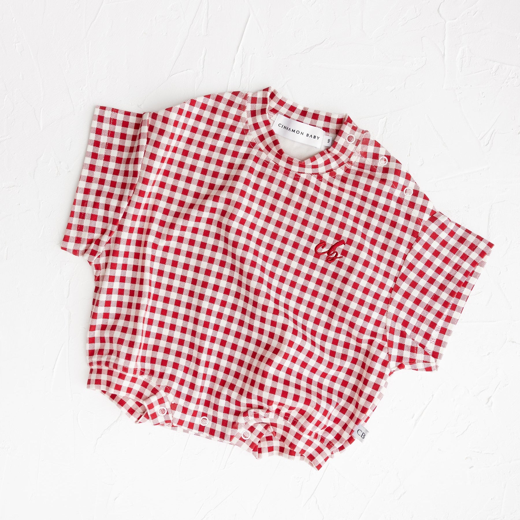 Red and white checkered shirt on a white background by Cinnamon Baby - Merci Collection. 