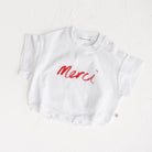 White t-shirt with red 'Merci' text on a white background, Merci collection by Cinnamon Baby exclusive to white Fox & Co