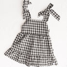 Cinnamon Baby Merci collection | Black and white checkered dress with bow straps on a white background