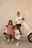 White baby t-shirt romper with crossiant pattern on toddler, scooter, kids, Cinnamon Baby Merci collection