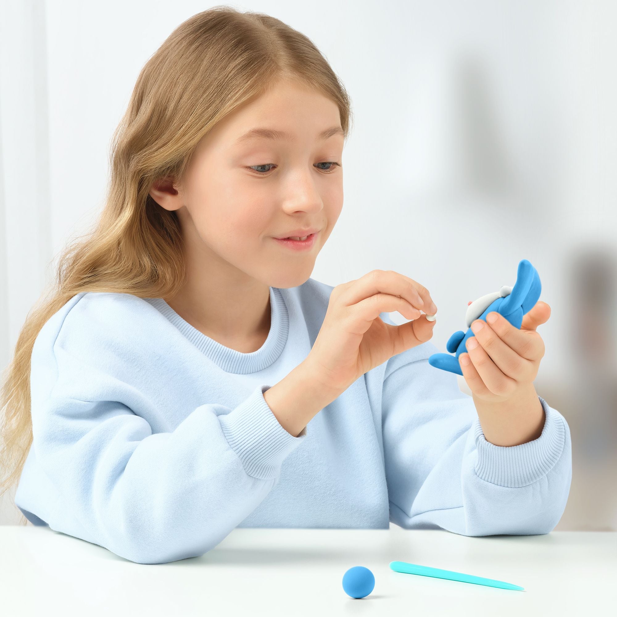 Young girl playing with a blue hey clay creation 