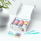 Box of colorful clay rolls with a plant and card in the background