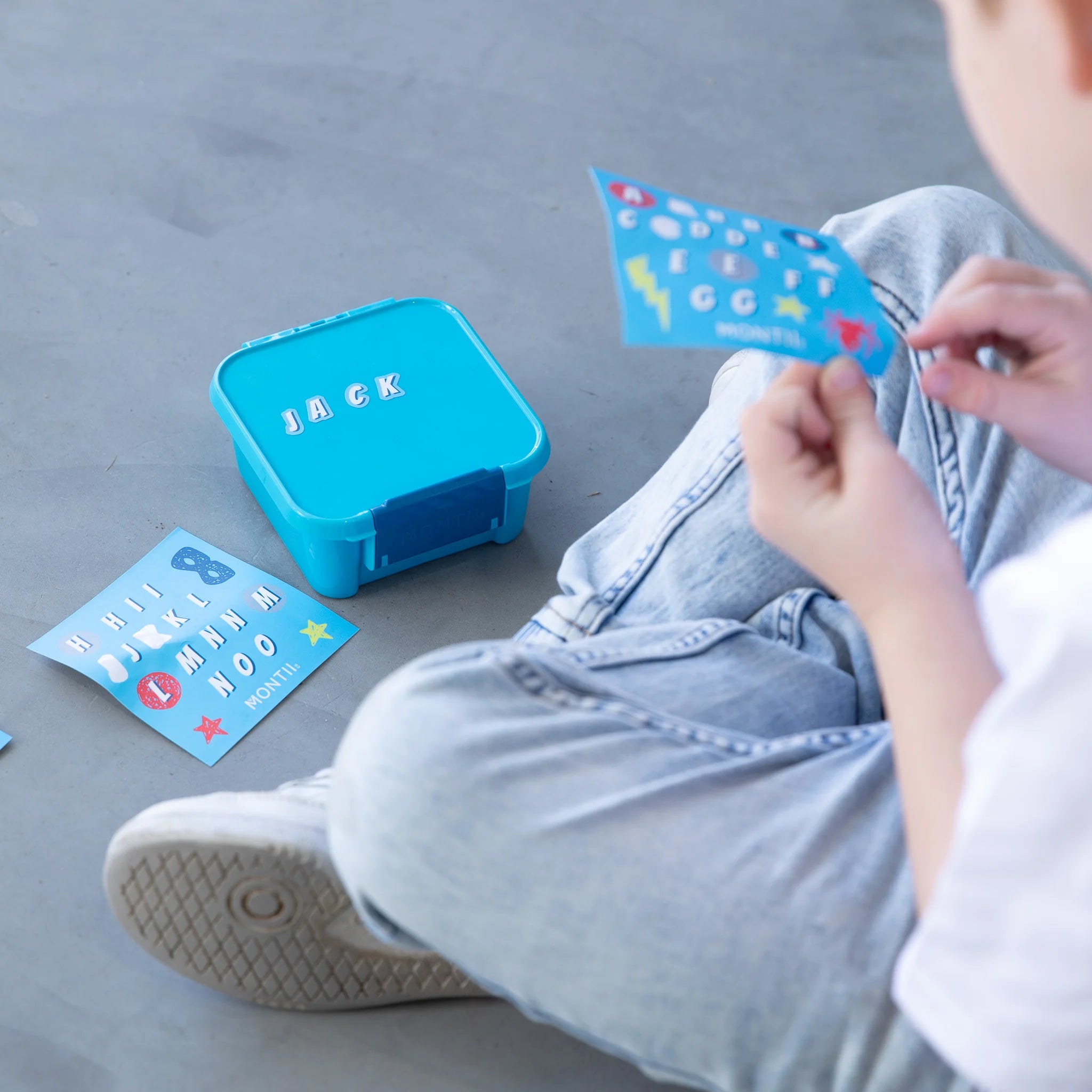 Child holding MontiiCo Bento Two Coastal lunchbox for school lunch