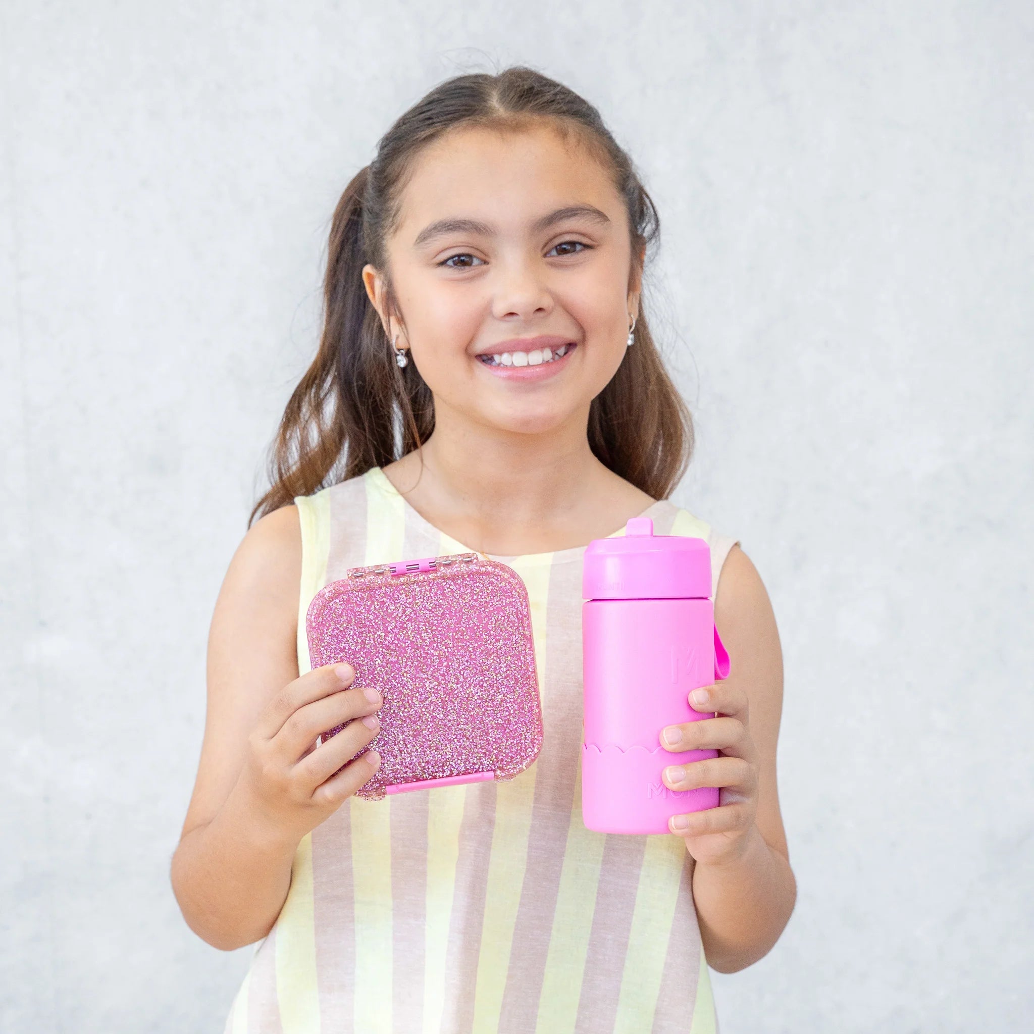 Child holding MontiiCo Bento Two in Floss Glitter – pink glitter lunchbox for school