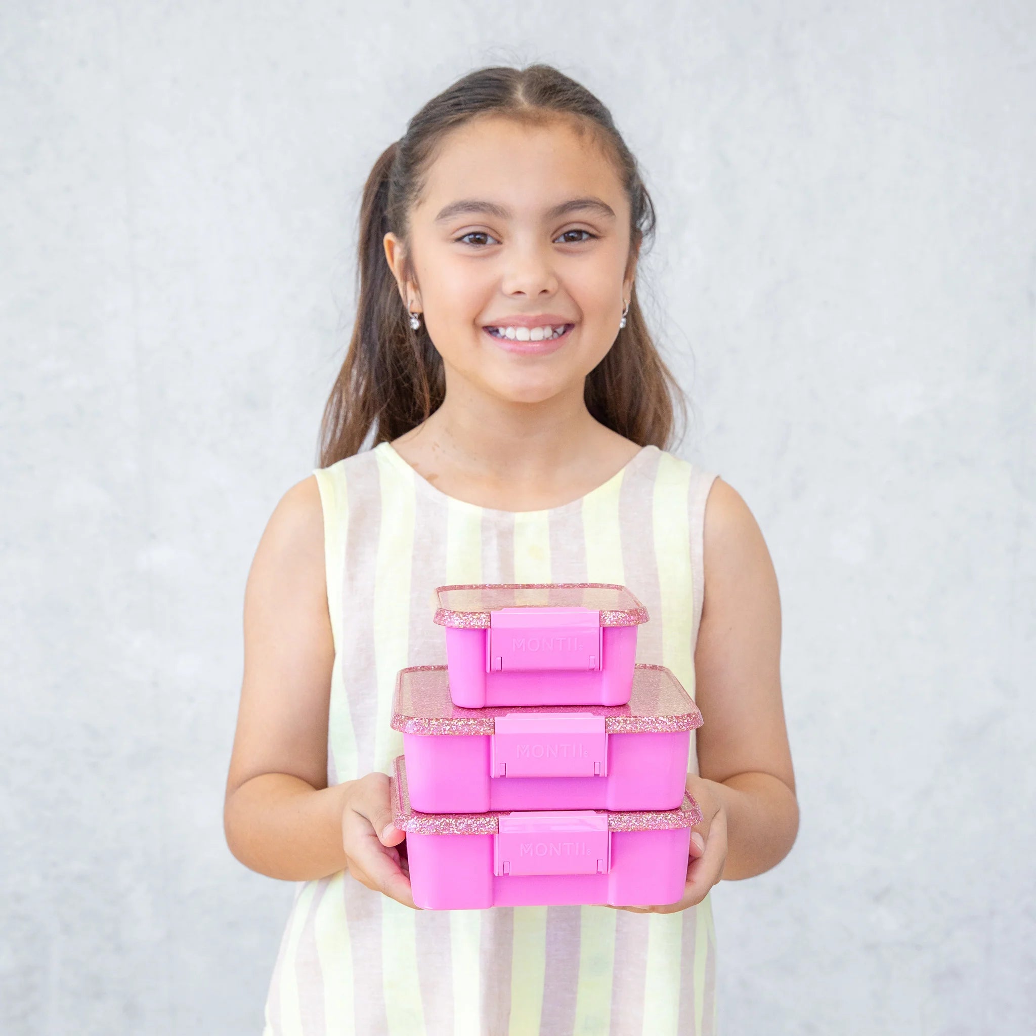 Child holding MontiiCo Bento Two in Floss Glitter – pink glitter lunchbox for school